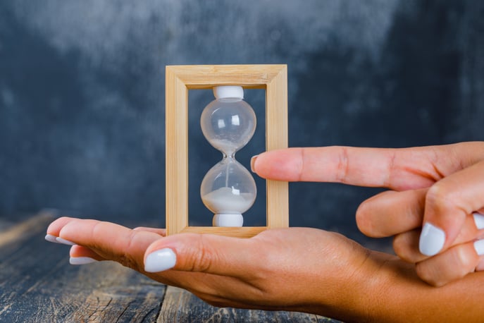 hands-holding-hourglass-showing-time