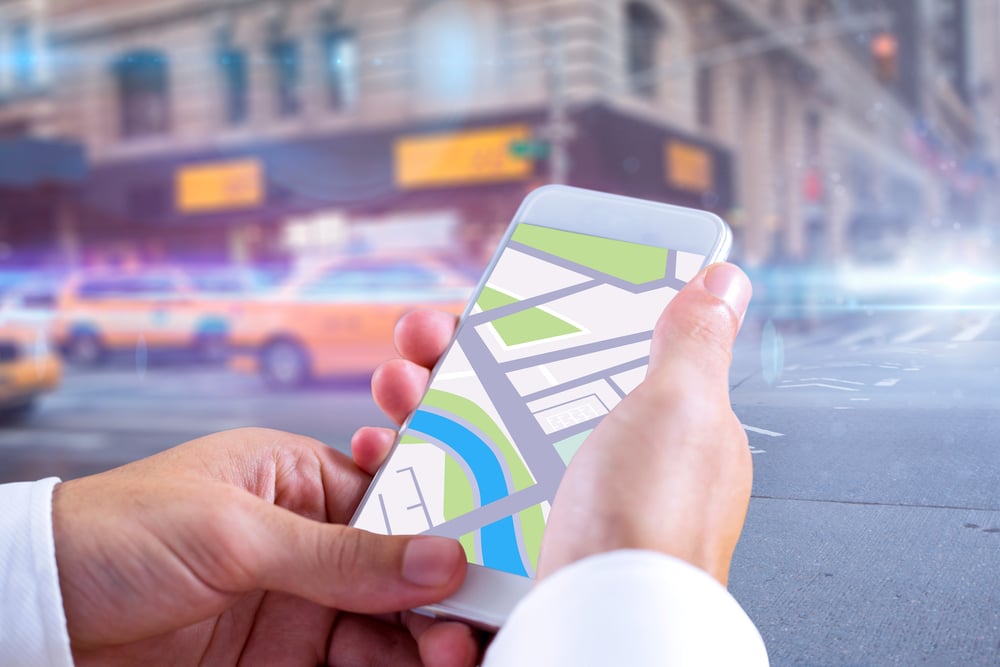 Man using map app on phone against blurred new york street